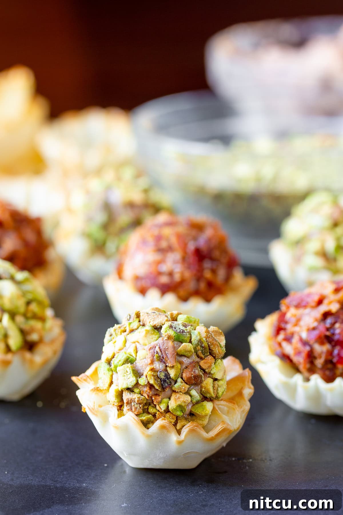 Mini cheese balls in small fillo cups lined up.