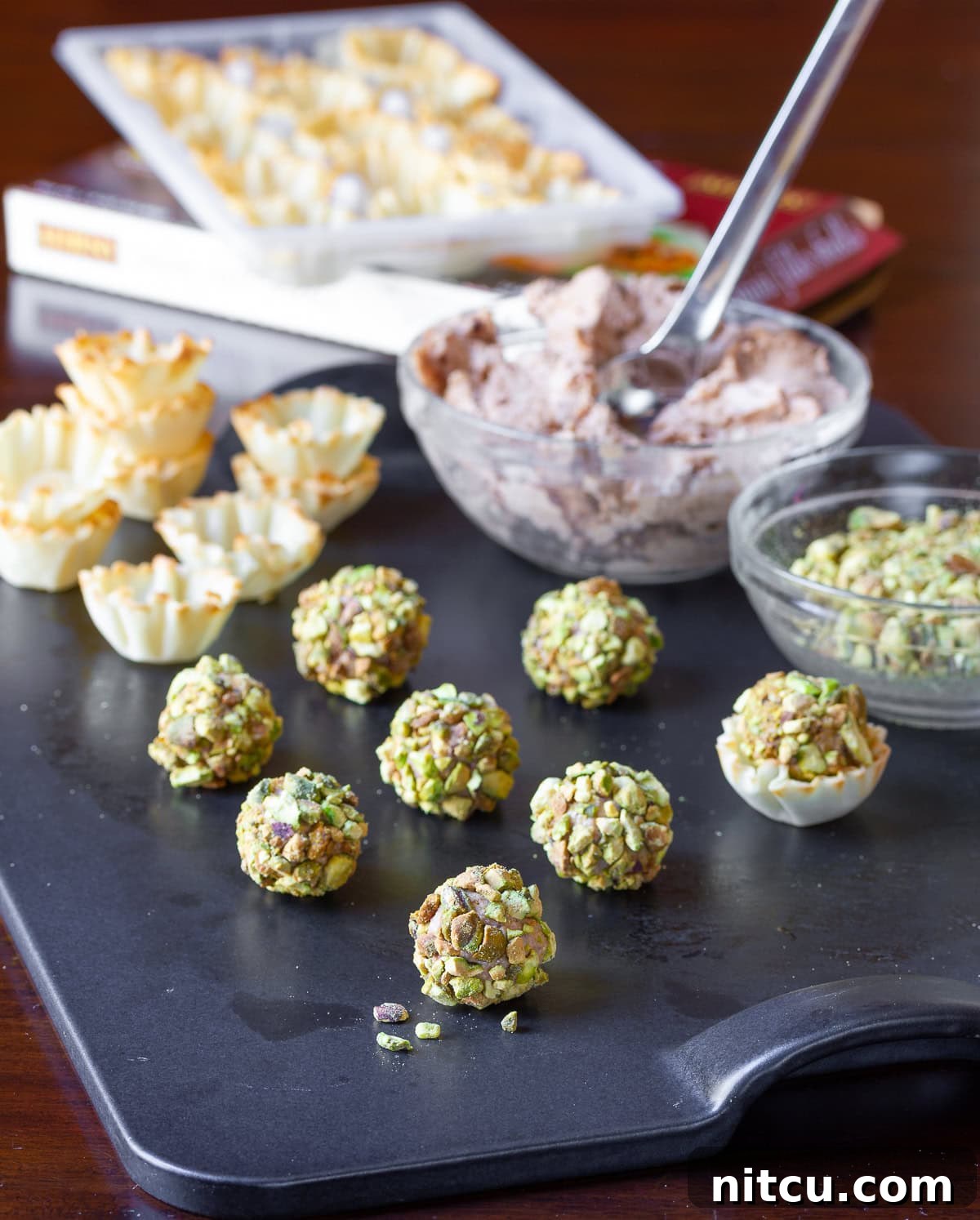 Assembling cheeseballs on a cutting board.