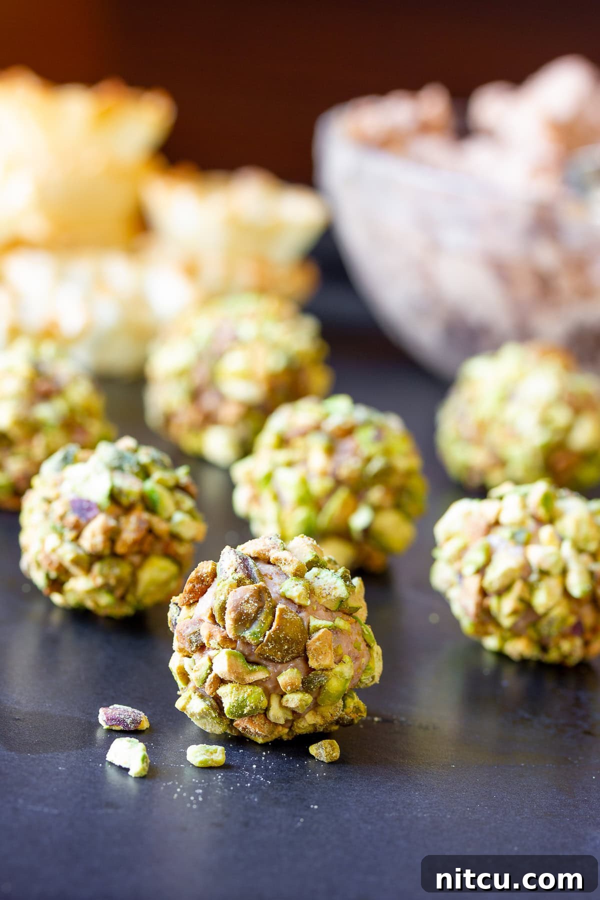 Close up shot of a cheese ball rolled in crushed pistachios.