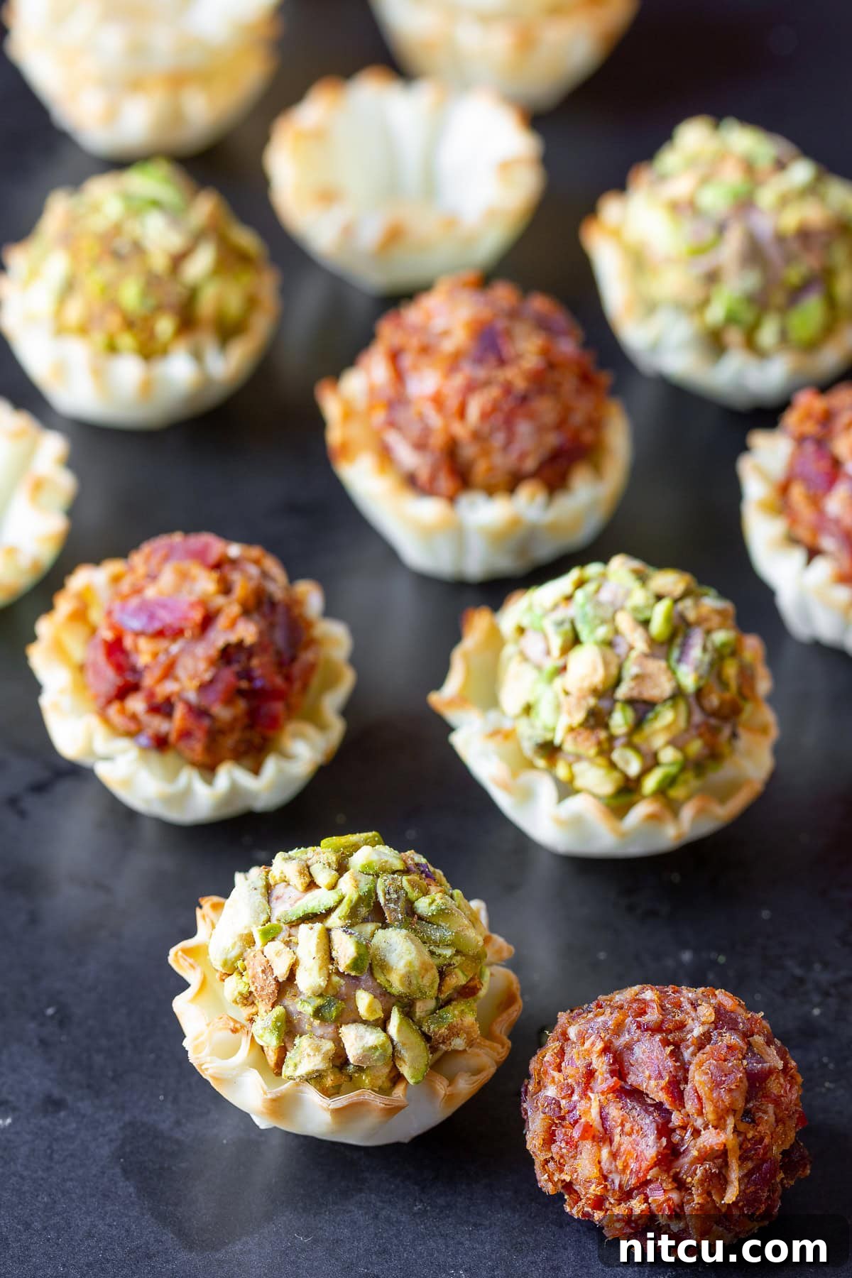 mini cheese balls on a cutting board with some of them in fillo cups.