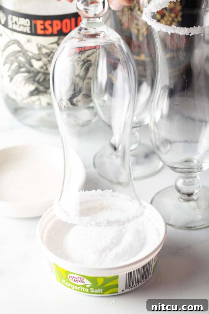 Dipping a the rim of a hurricane glass into a dish of salt.