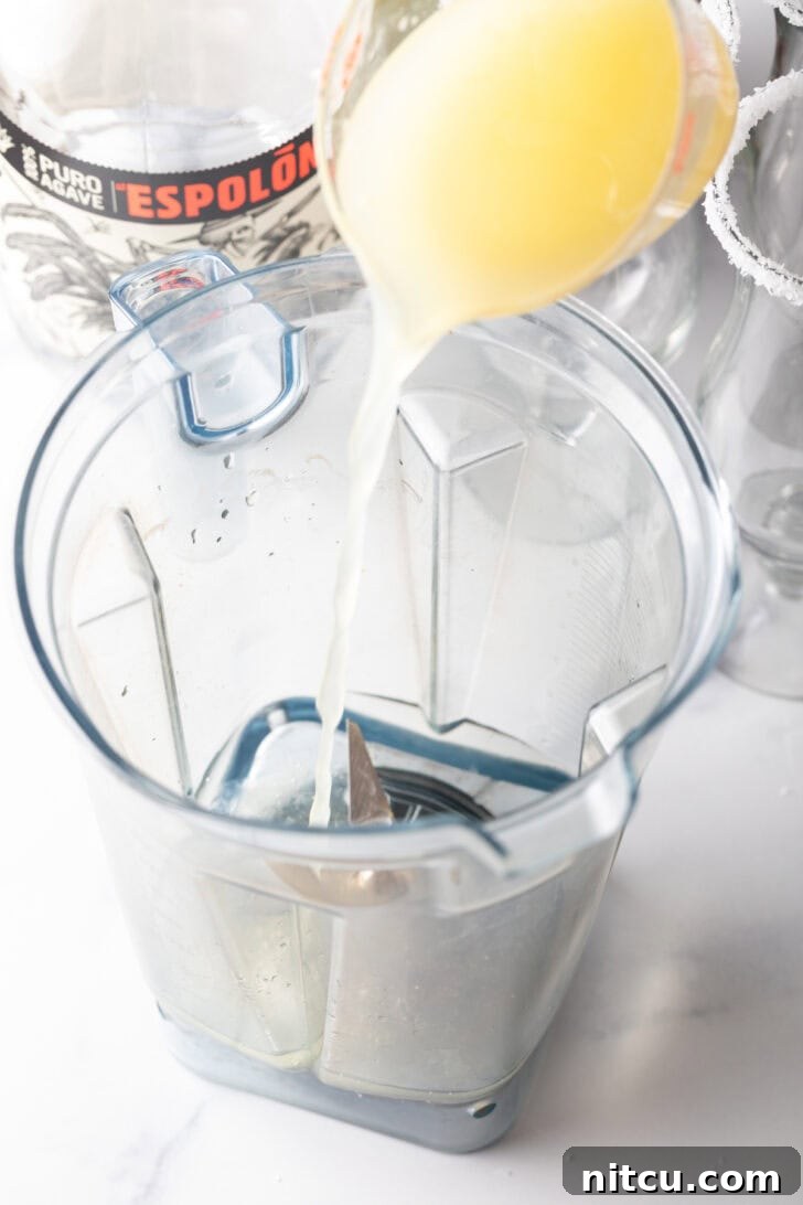 Pouring citrus juice into a blender jar.