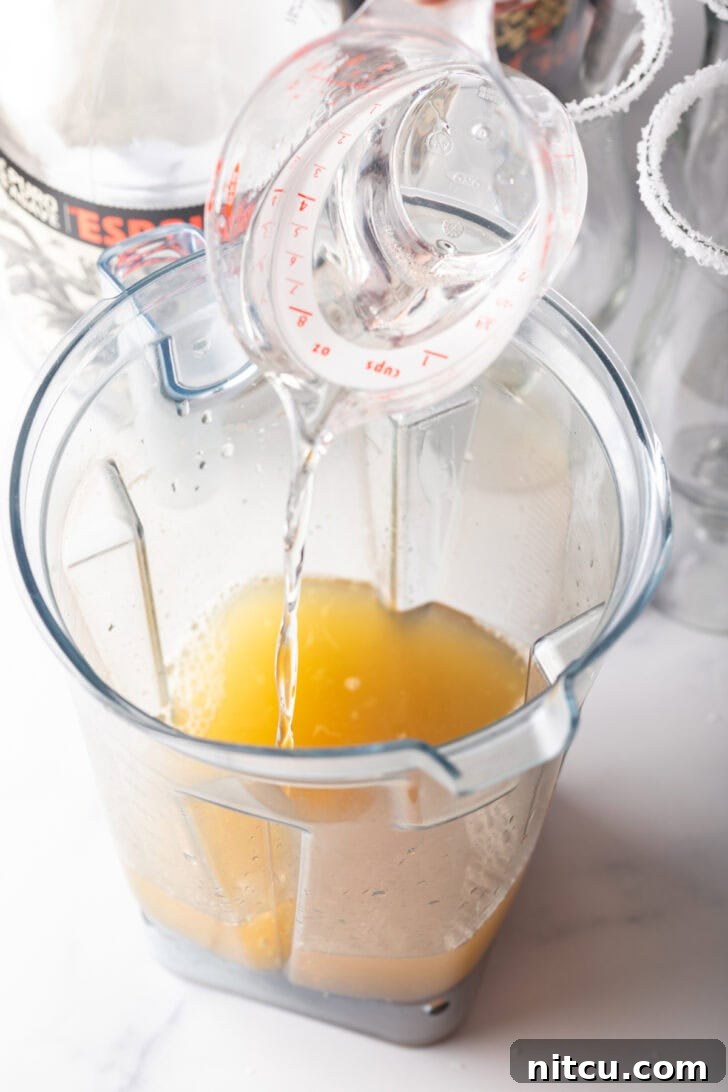 Adding clear alcohol to a blender pitcher.