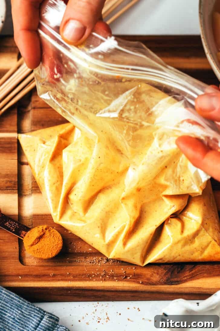 A large Ziploc bag meticulously filled with chicken pieces thoroughly coated in a rich satay marinade.
