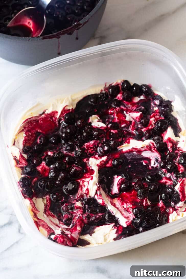 Swirling cooked blueberry filling into creamy vanilla ice cream.