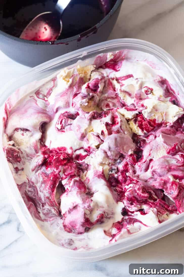Plastic tub filled with freshly made blueberry pie ice cream, ready for freezing.