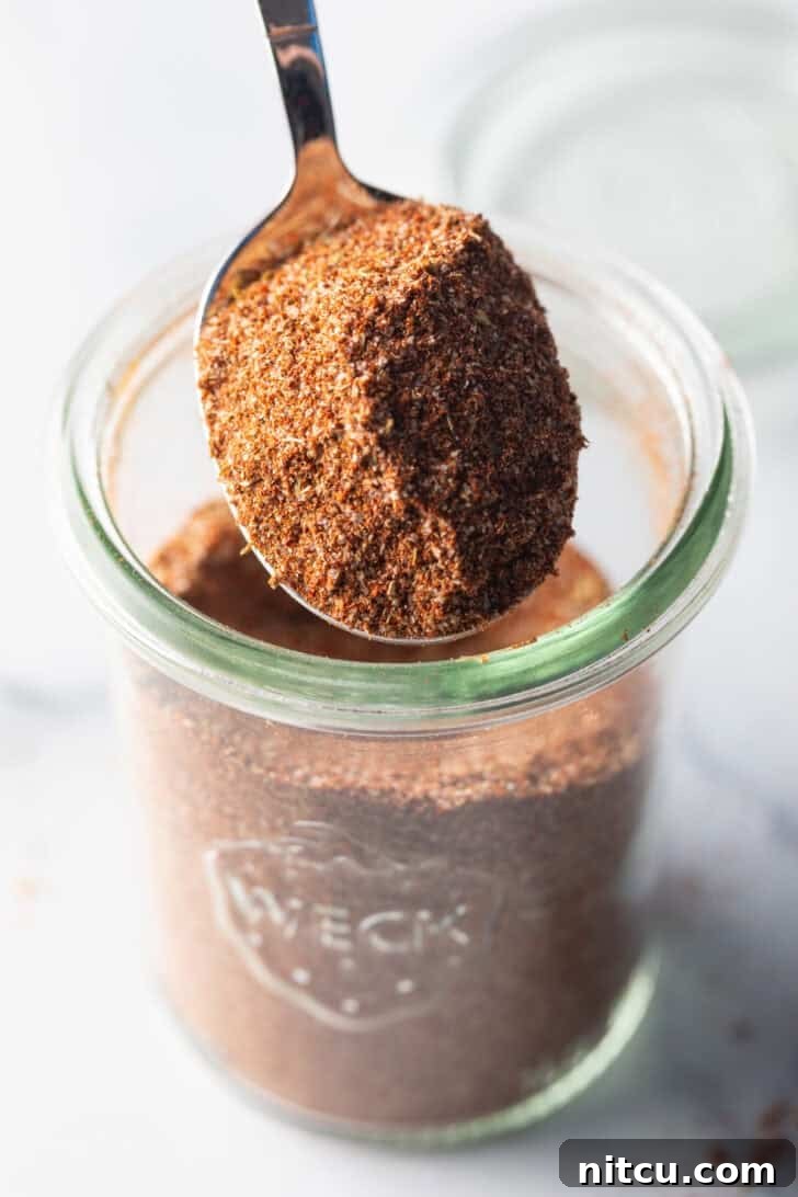 A spoonful of rich, homemade chicken taco seasoning held up, showcasing its beautiful color and texture. Perfect for enhancing chicken dishes.