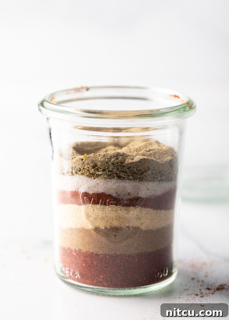 A close-up view of vibrant spice layers settled at the bottom of a tall glass jar.