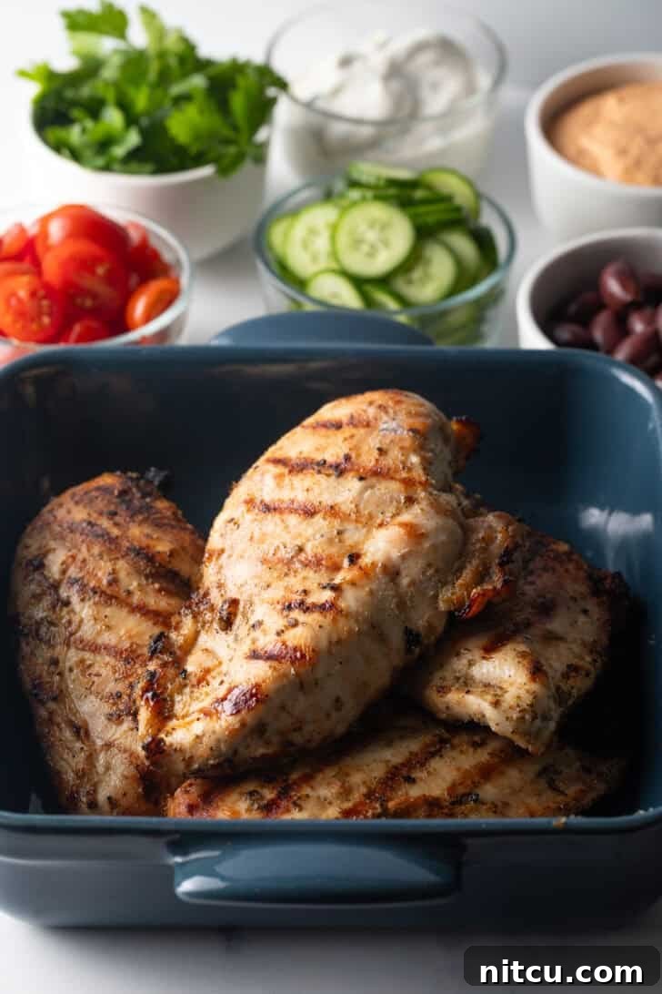 4 grilled chicken breasts in a blue square baking dish.