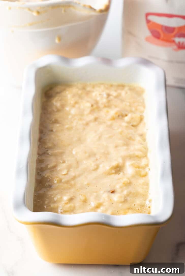 Smooth banana bread batter poured into a clean white loaf pan, ready for baking.