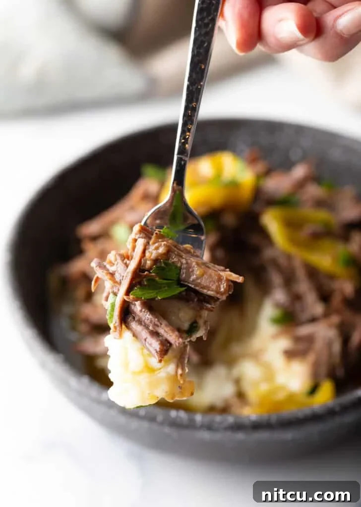 Hand holding a forkful of pot roast to camera.