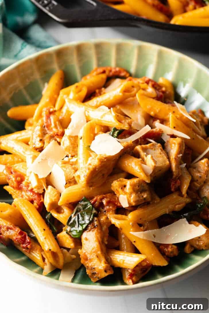 A vibrant green bowl filled with spicy Marry Me Chicken Pasta, garnished with fresh basil leaves.