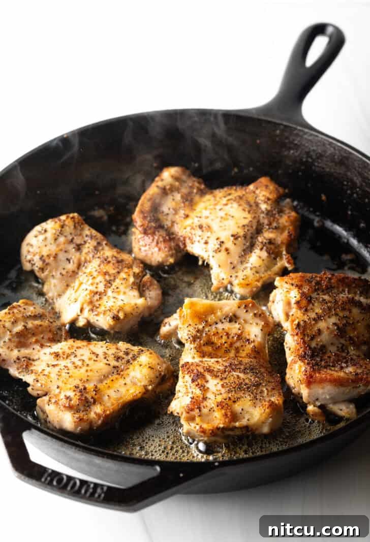5 cooked chicken thighs with a beautiful sear in a cast iron skillet.