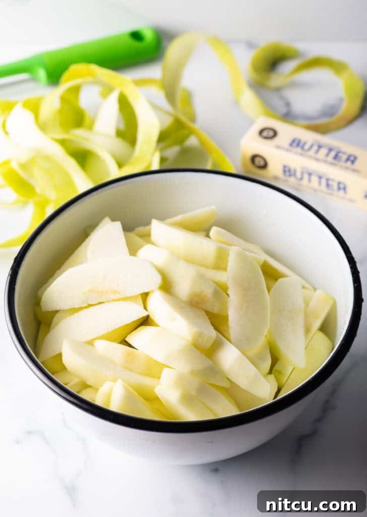 A white bowl filled with freshly sliced apple wedges, coated in lemon juice.