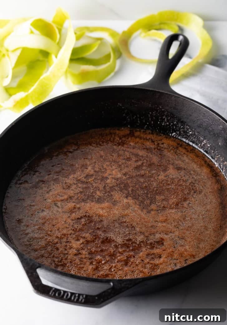 Caramelized sugar, butter, and spices melting together in a cast iron skillet, forming the glaze base.