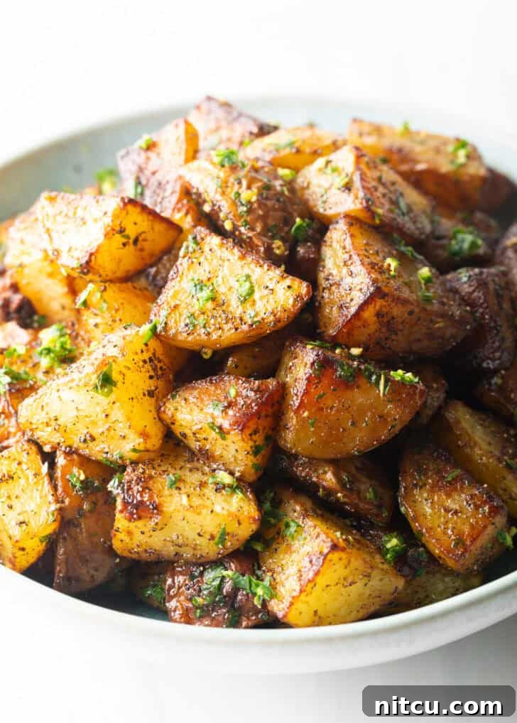 White bowl brimming with pieces of golden crispy Yukon potatoes.