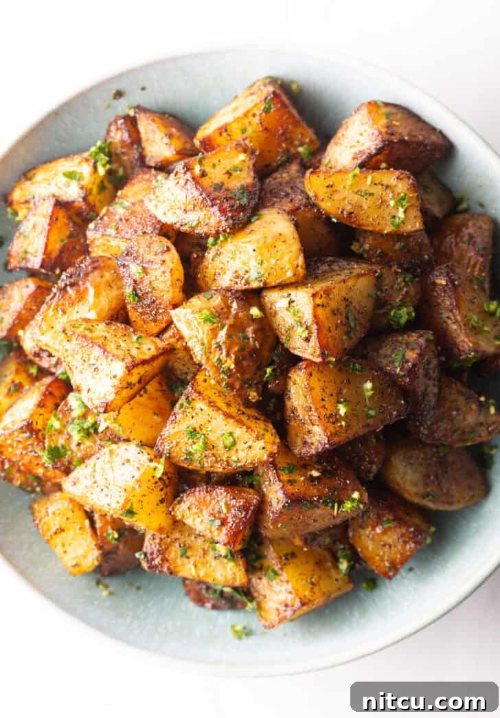 Top down view of a white bowl brimming with pieces of golden crispy Yukon potatoes.