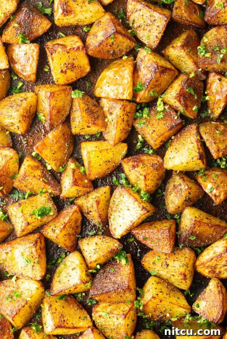 Top down view a rimmed baking sheet covered with chunks of crispy golden potatoes.