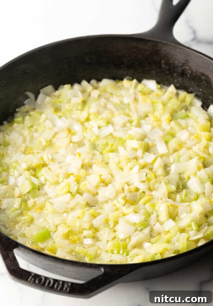 Sautéing chopped celery and onion in melted butter in a cast iron skillet.