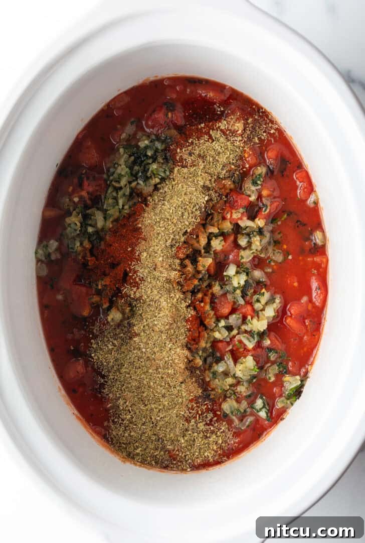 Top down view white crock pot with salsa and cooked herbs.