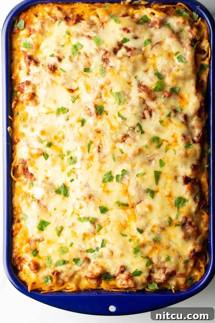 Top down view of a bubbly, golden brown cheesy baked spaghetti casserole, fresh from the oven.