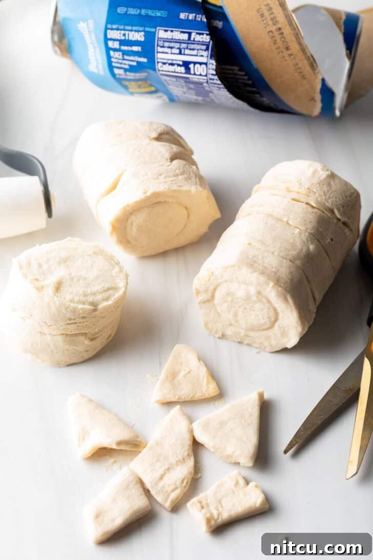 Small, triangular pieces of biscuit dough neatly arranged, cut from flattened biscuits, ready to be added to the slow cooker.