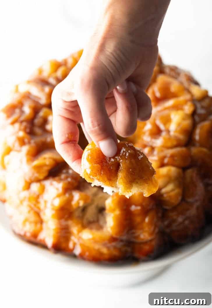 Hand pulling a baked dough monkey ball from the loaf.