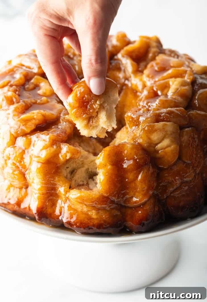 Hand pulling a baked dough monkey ball from the loaf.
