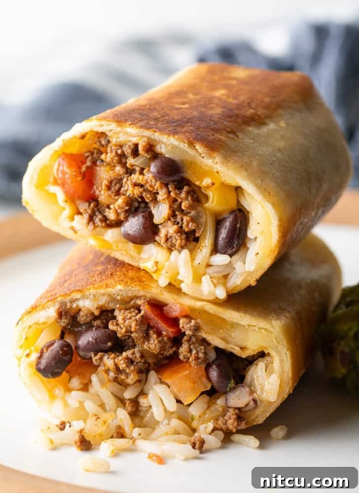 Two halves of a beef and cheese burrito stacked on top of each other, showcasing the delicious fillings.