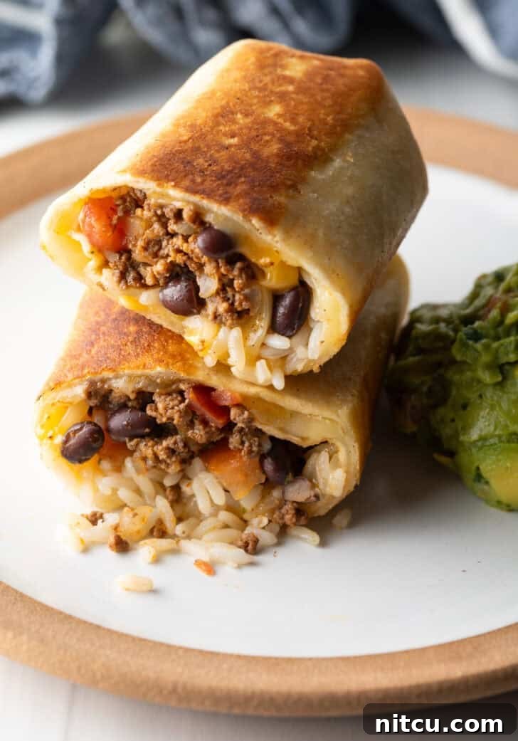 Two halves of a beef and cheese burrito stacked on top of each other, ready to be enjoyed.
