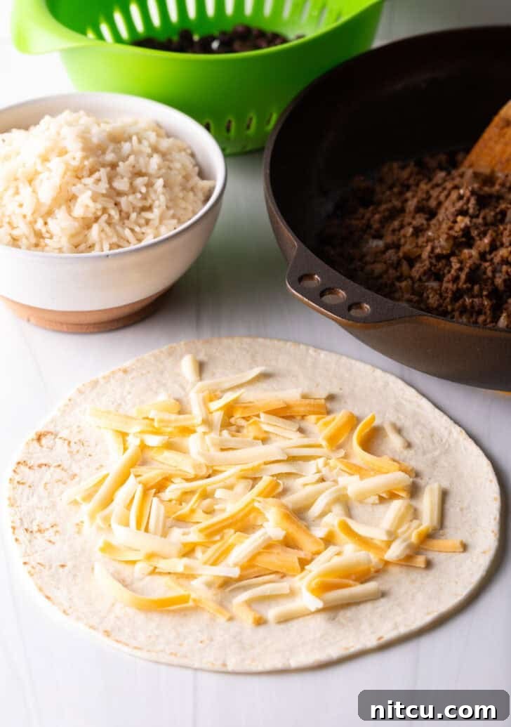 Open-faced flour burrito with shredded cheese, a foundational layer before adding other fillings.
