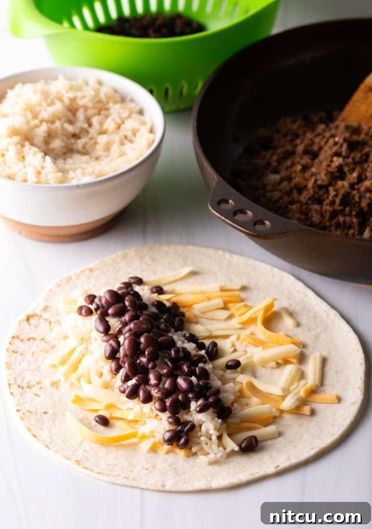 Open-faced flour burrito with shredded cheese, beans, and ground beef, perfectly layered for rolling.