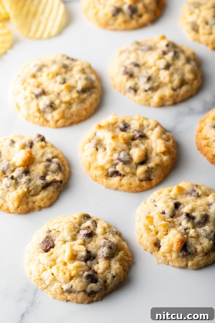 A fresh batch of golden-brown potato chip cookies cooling on a white baking rack, showcasing their slightly irregular shapes and the visible crunch of the chips.