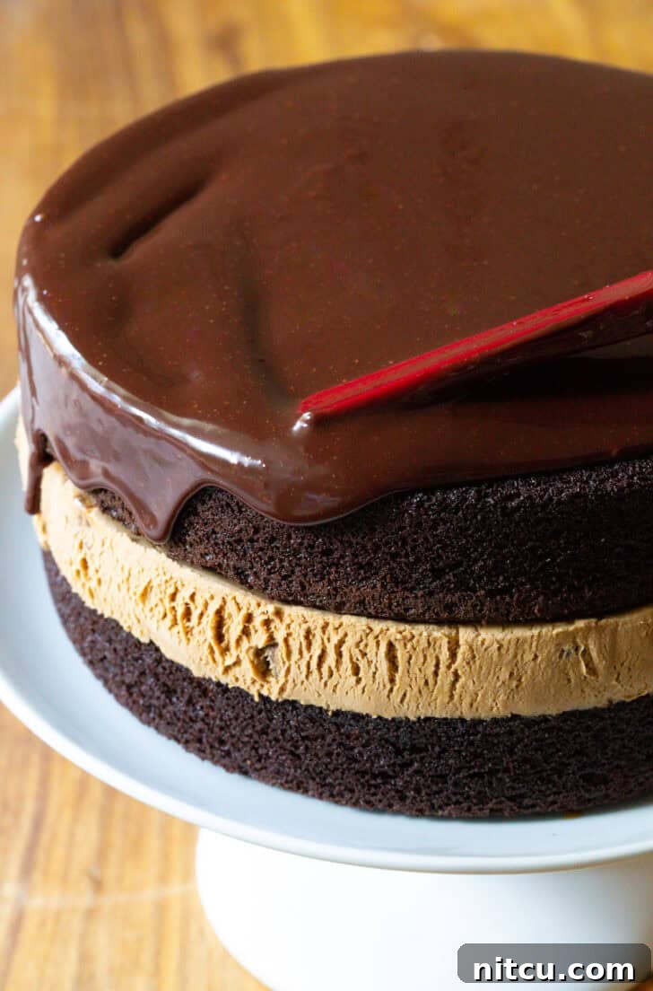 Covering chocolate and caramel ice cream cake with dripping chocolate ganache.