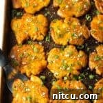 Top down view of 15 golden smashed potatoes on a baking sheet.