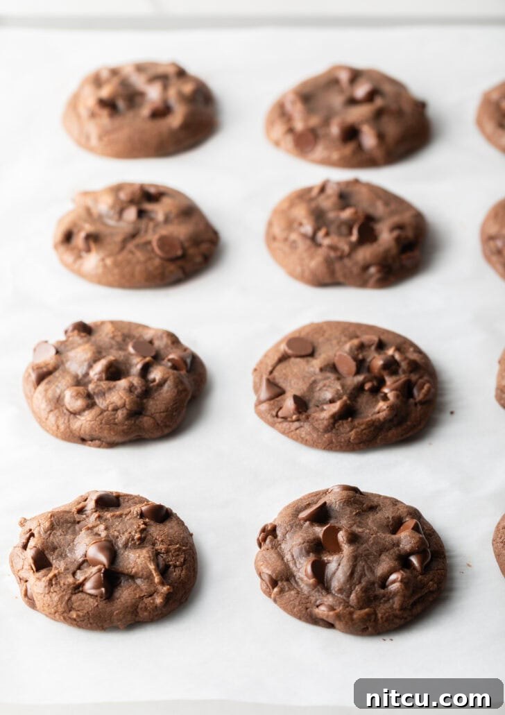 4 baked chocolate hazelnut cookies on a baking sheet.