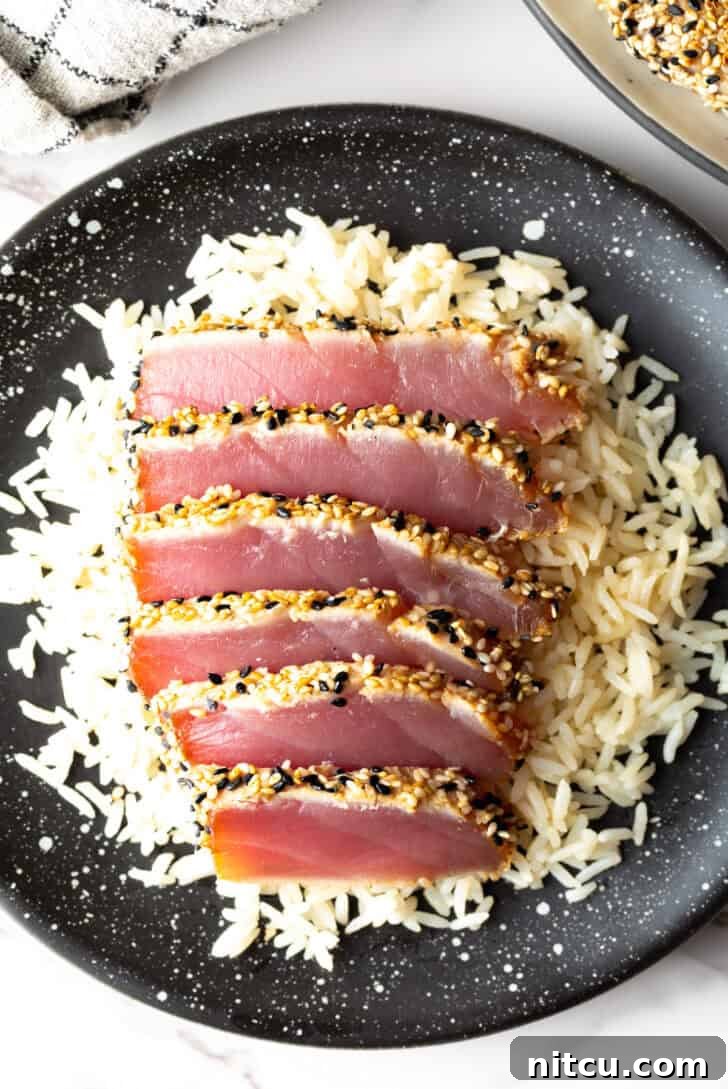 Top-down view of six perfectly seared ahi tuna slices presented elegantly on a bed of fluffy white rice.