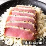 Six slices of seared ahi tuna on a bed of white rice.