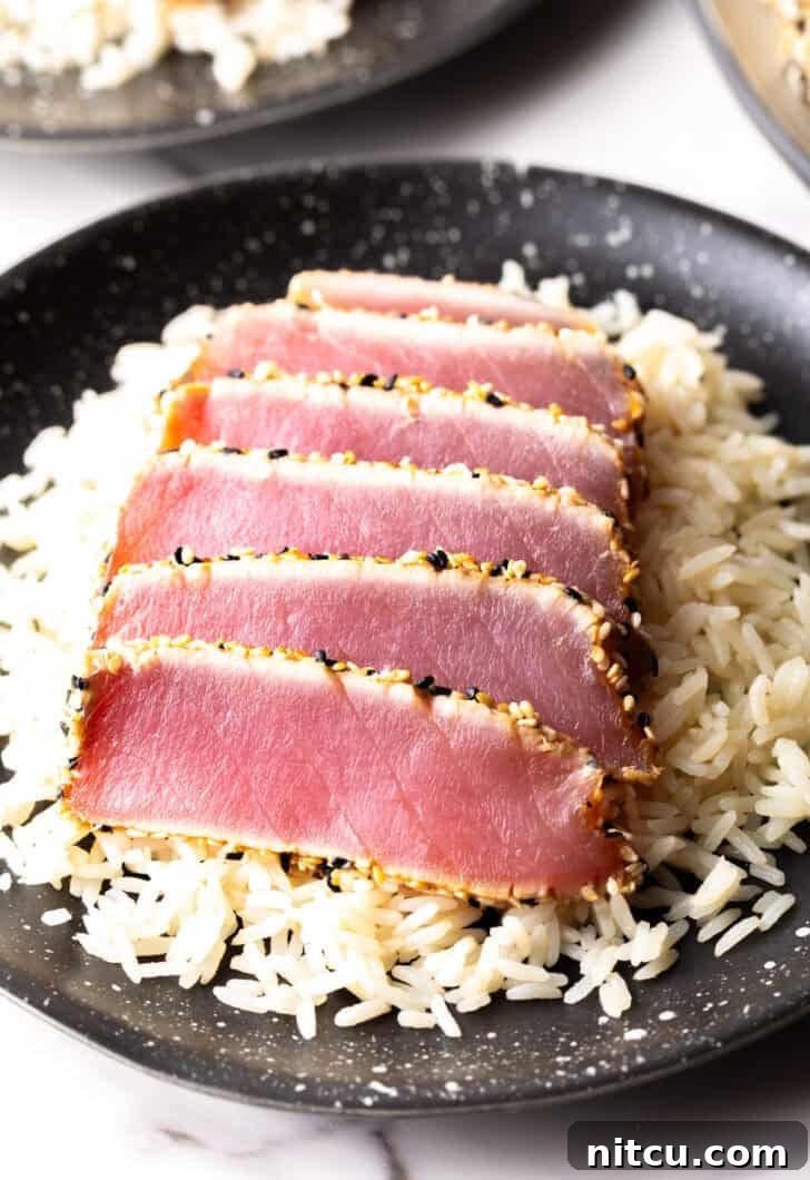 Six perfectly seared ahi tuna slices arranged on a bed of fluffy white rice.