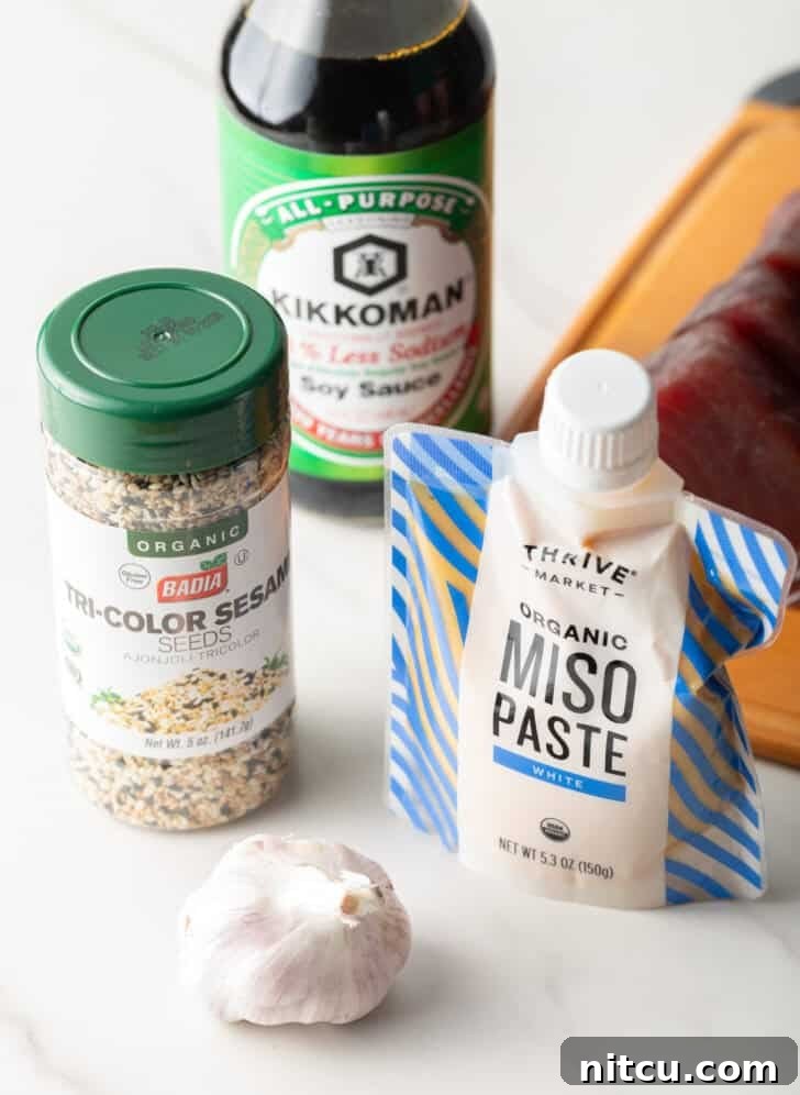 Ingredients for yellowfin marinade: Jar of tricolor sesame seeds, bottle of low-sodium soy sauce, a whole bulb of garlic, and a squeeze pack of white miso paste.