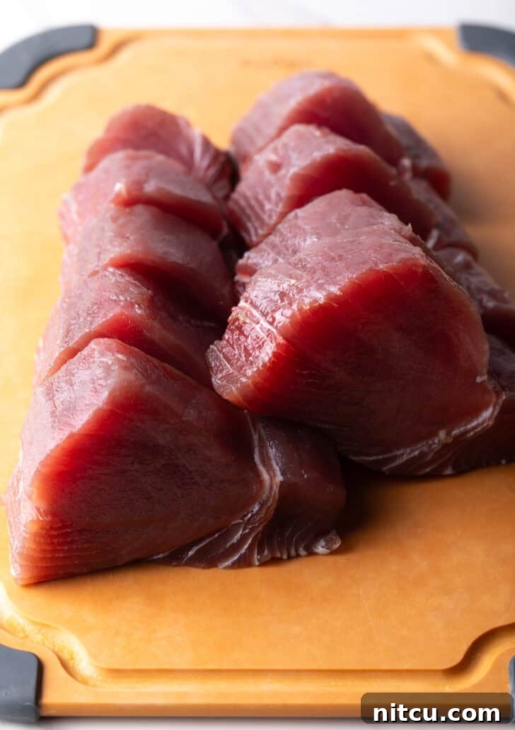 Slices of raw ahi tuna uniformly cut on a cutting board.