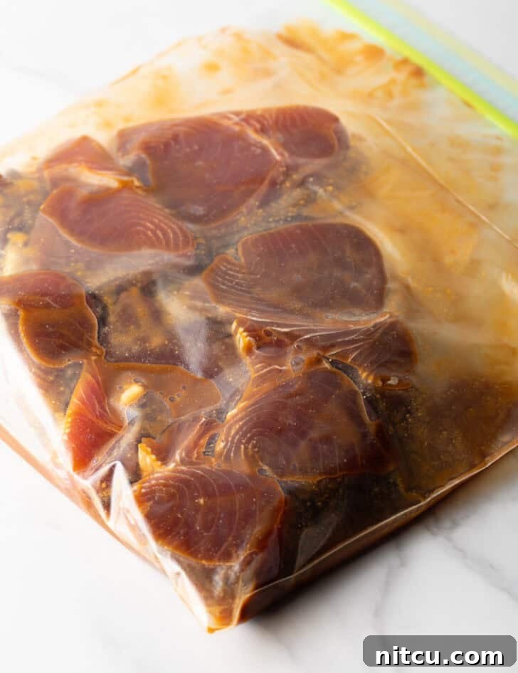 Several tuna steaks marinating in a ziploc bag, ensuring full flavor absorption.