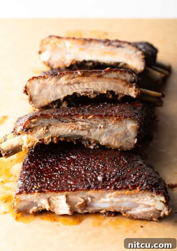 Perfectly sliced St. Louis style ribs stacked on a wooden cutting board, ready to serve.