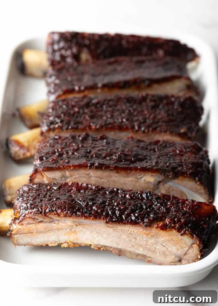 Six perfectly grilled barbecue pork ribs, neatly sliced and arranged on a white serving tray.