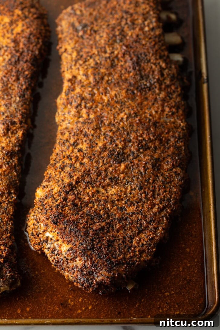 Cooked St. Louis ribs in an oven tray after the initial baking phase.