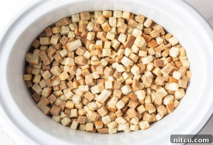 Dried bread cubes in a white crock pot.