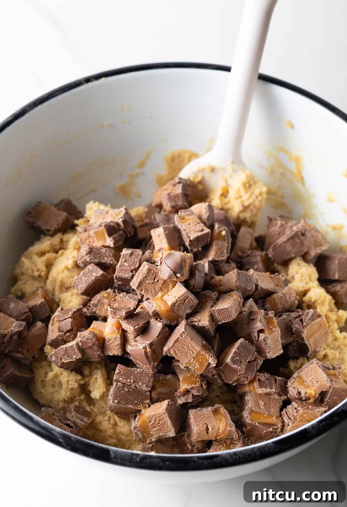 A close-up shot of chopped Milky Way bars, showcasing the distinct layers of chocolate, caramel, and nougat.