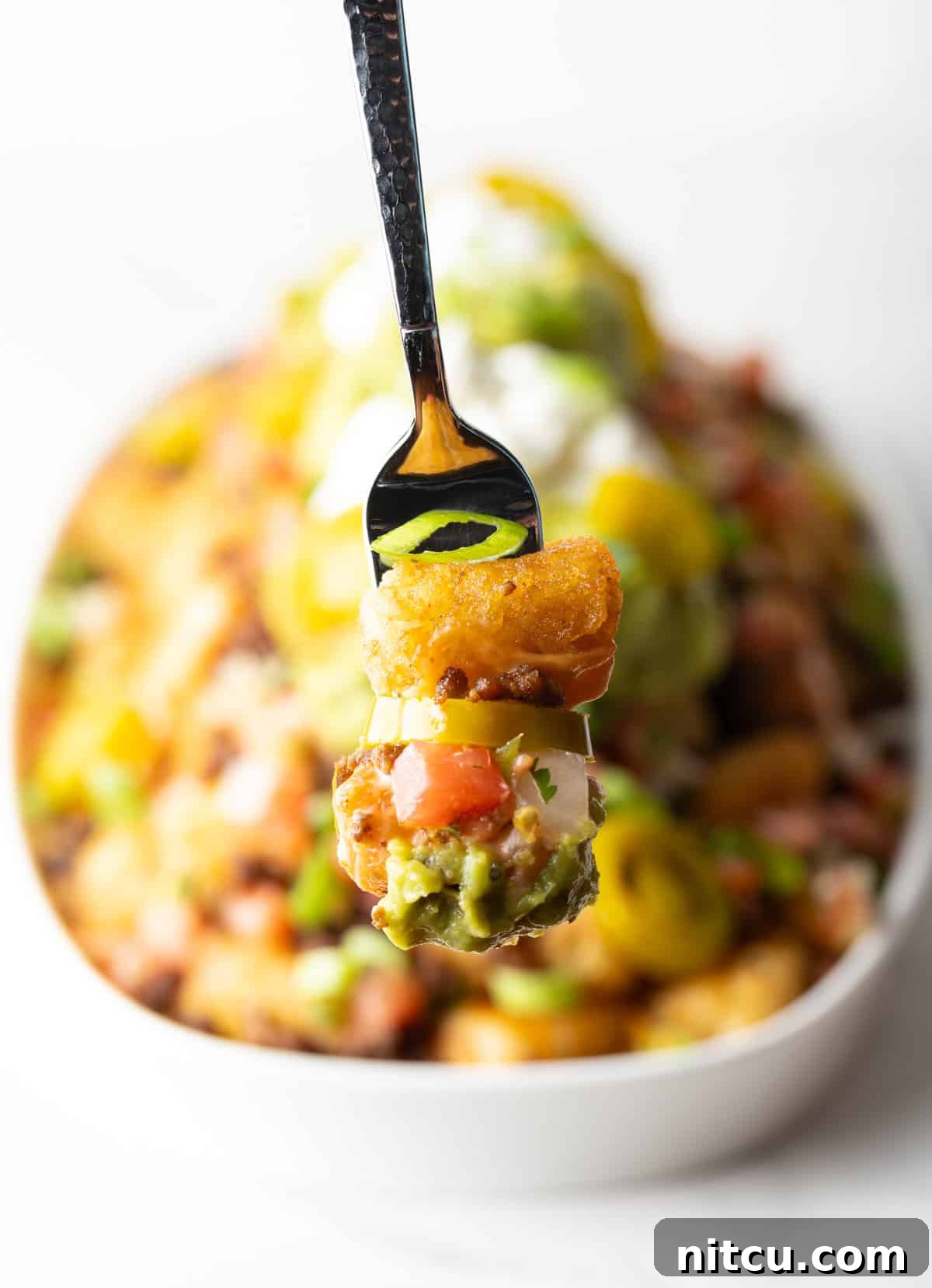 Forkful of totchos held to camera.
