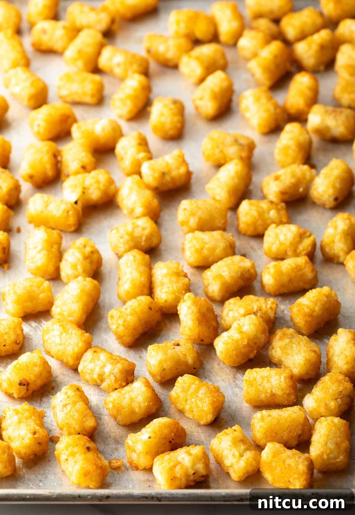 A baking sheet filled with crispy baked tater tots.