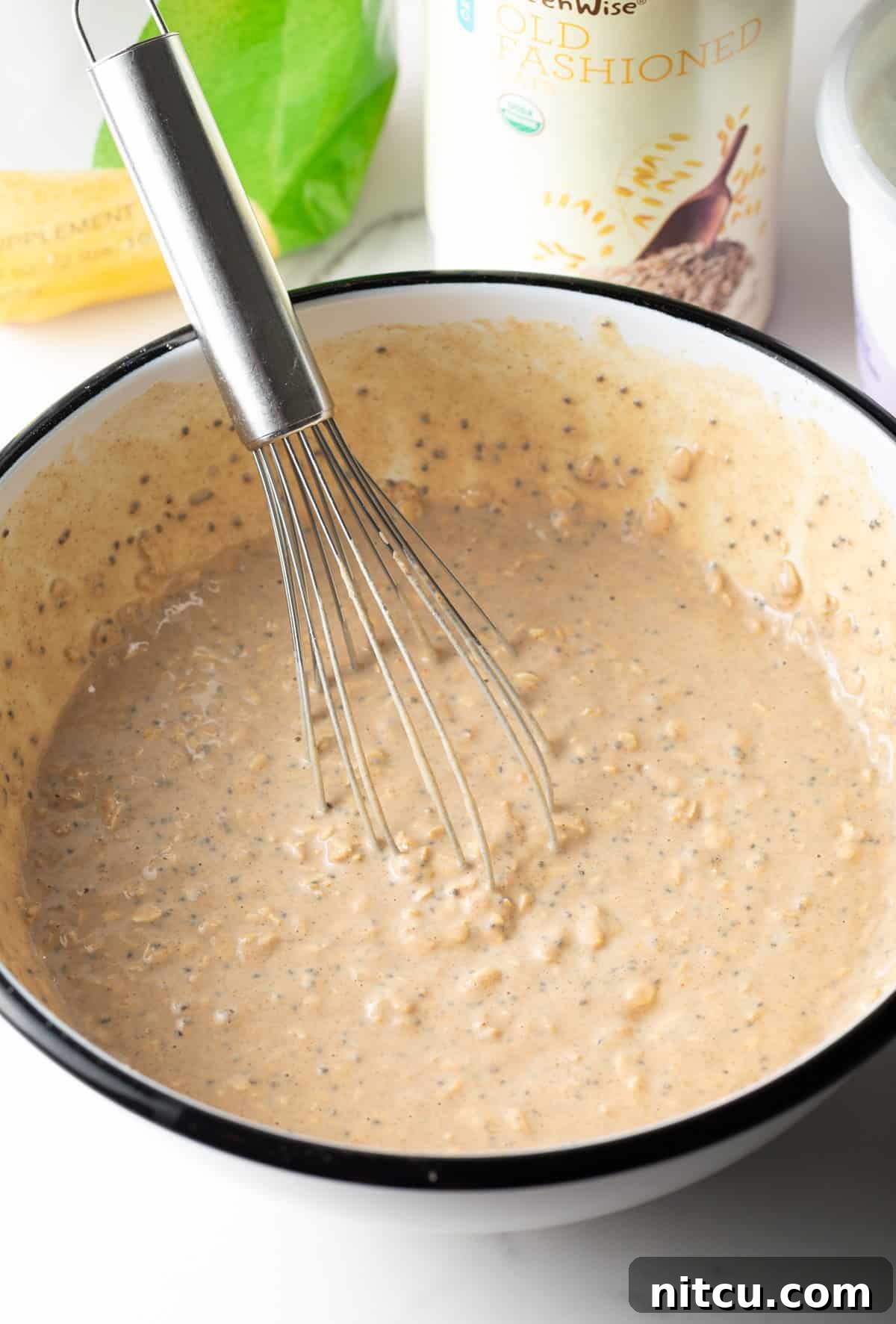 A whisk stirring all ingredients for high protein overnight oats.